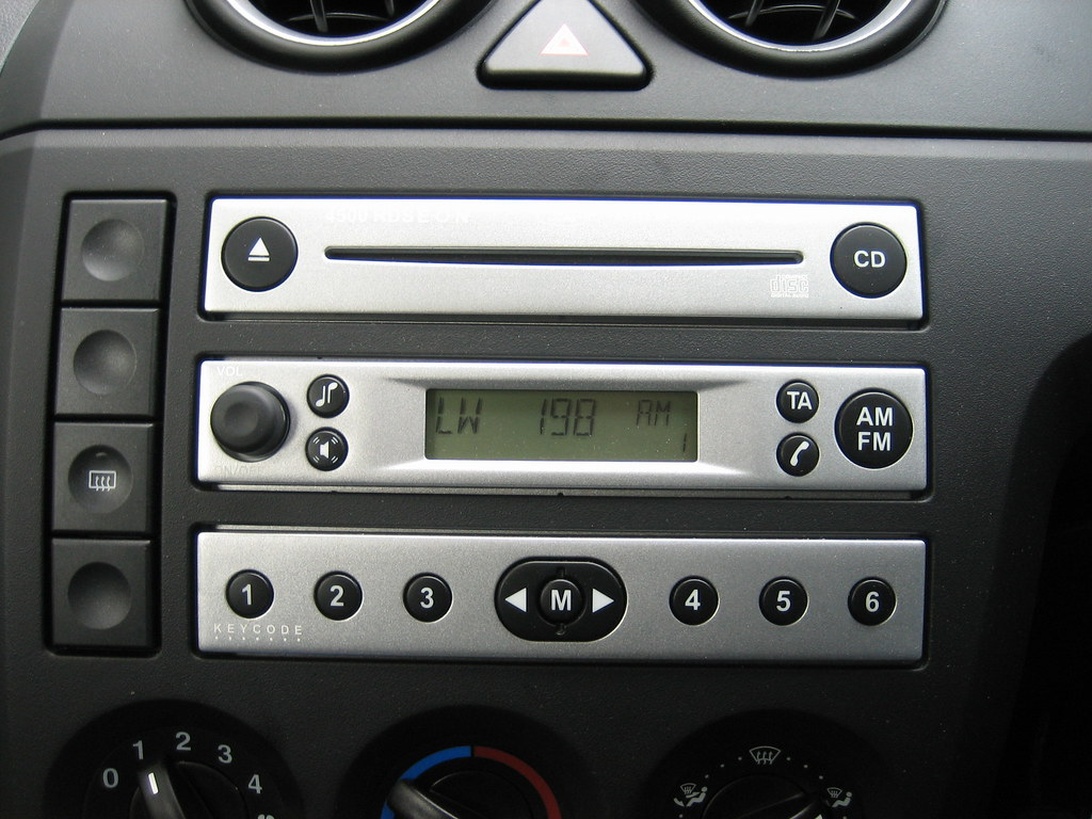 Et klassisk bilradioanlæg med både CD-afspiller og AM/FM-radio, der viser traditionel bilunderholdningsteknologi.